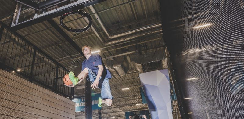 young adult slam dunks a ball in a hoop