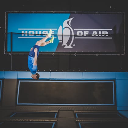 man vertical in front of house of air logo