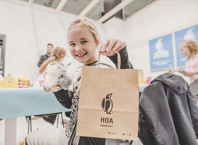 young women holding a gift bag from HOA featuring Geronimo the penguin