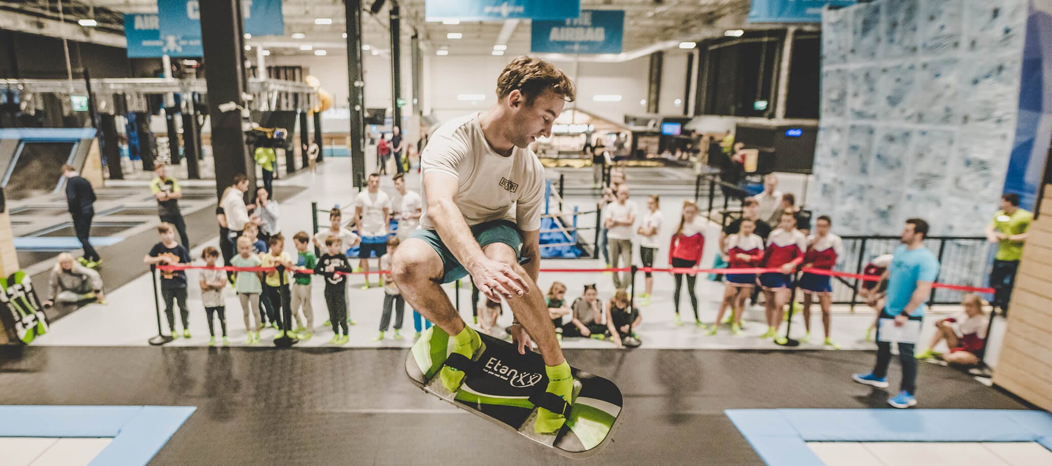 man strapped on to a board while others watch him jump in the background
