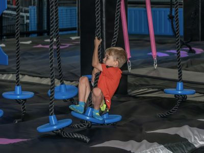 young boy swinging on the ninja course HOA