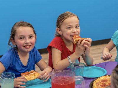 two young girls eat pizza at HOA